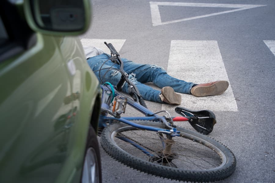 Bicyclist lying on the ground after being hit by a car