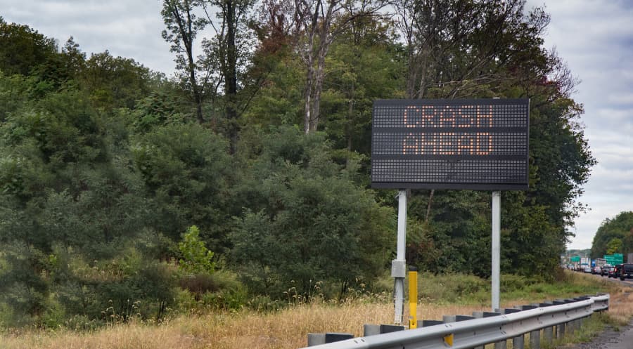 An electric sign warning motorists of a crash ahead with traffic backed up