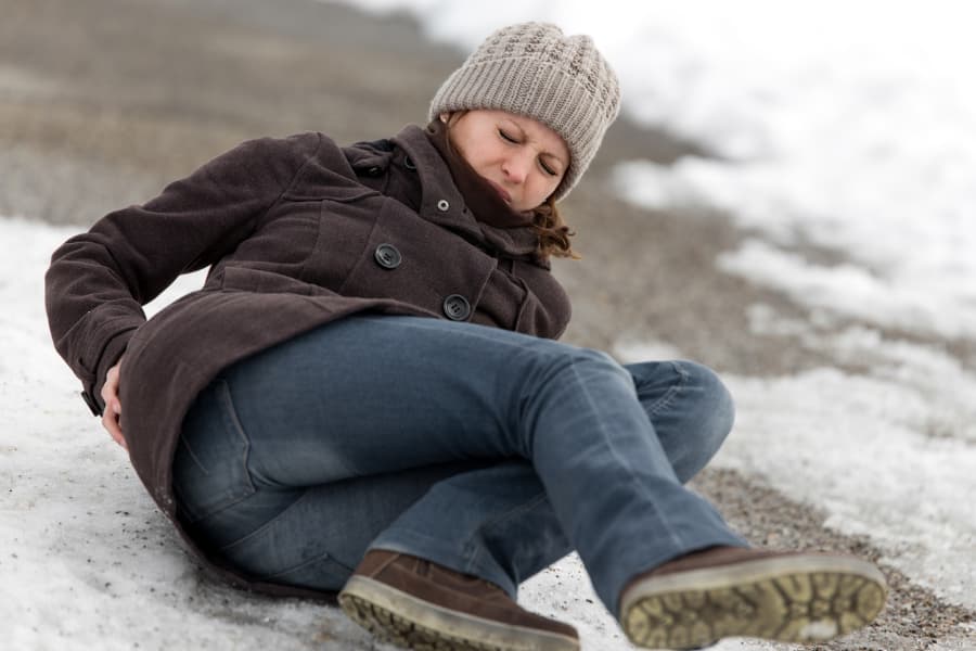 A woman checks herself for injuries after slipping and falling on ice