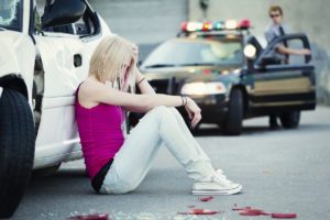 Girl Sitting Against Car Following Collision