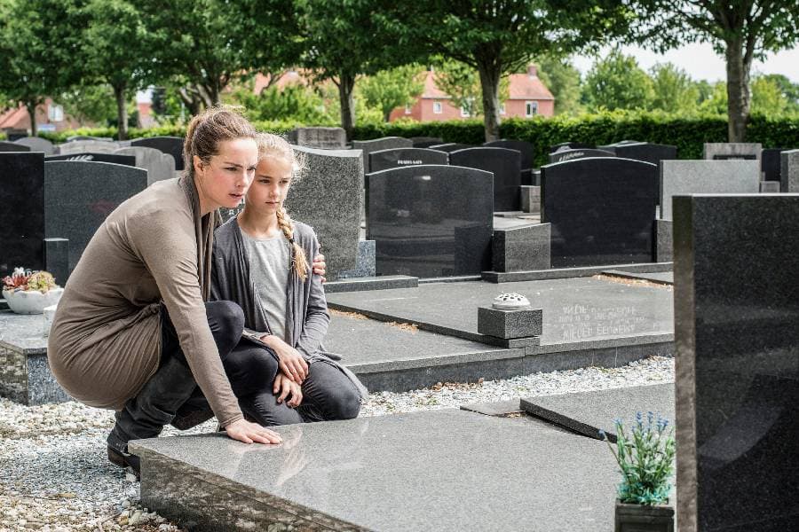 A mother and daughter visiting the grave of a deceased loved one.
