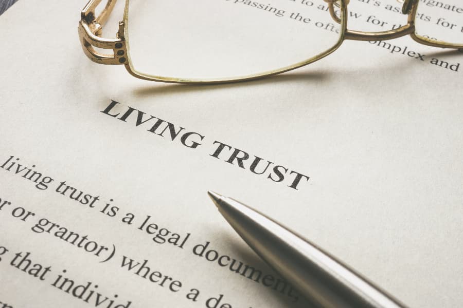 Close up of a living trust document with eyeglasses and a pen on top of it.